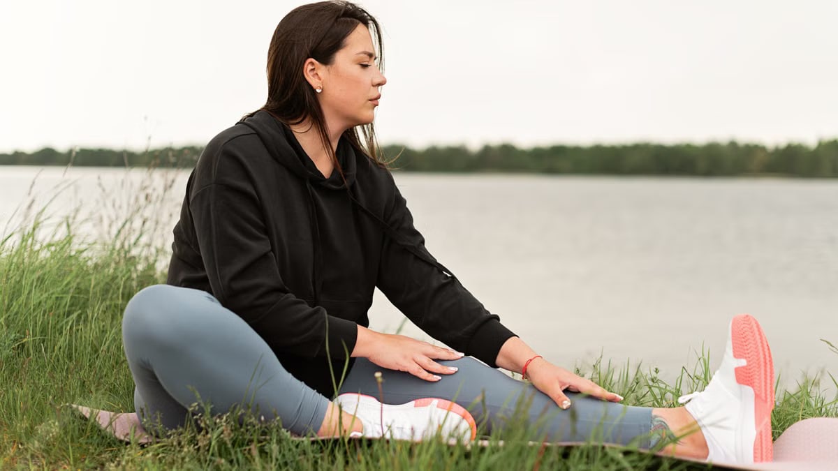 Serene outdoor yoga session by a lake with a woman stretching on a mat.